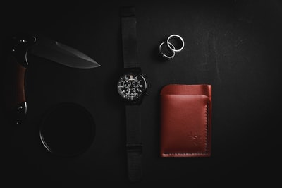 黑色皮带银色圆模拟手表和棕色皮革两褶的钱包
